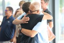 Student in black t-shirt hugging family member